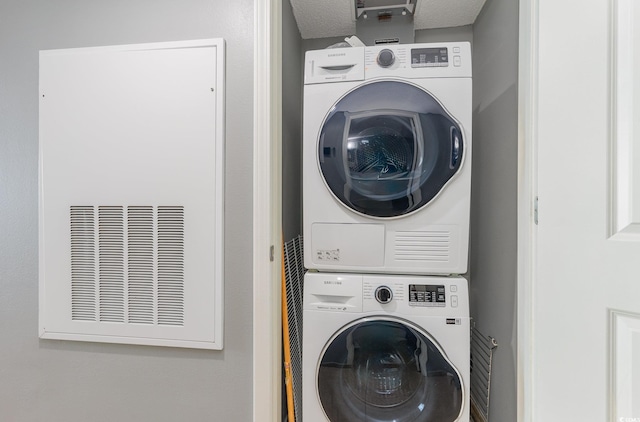 clothes washing area featuring a textured ceiling and stacked washing maching and dryer