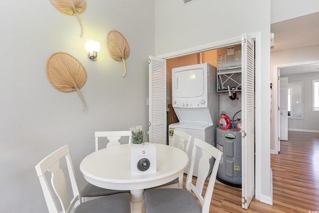 laundry room featuring a textured ceiling, hardwood / wood-style flooring, and stacked washer / drying machine