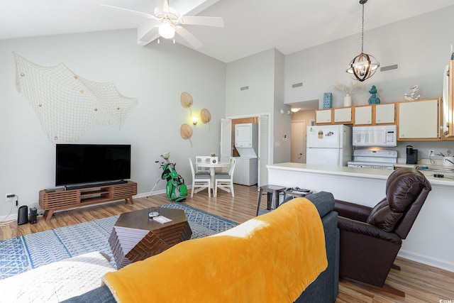 living room featuring ceiling fan with notable chandelier, light wood-type flooring, and high vaulted ceiling