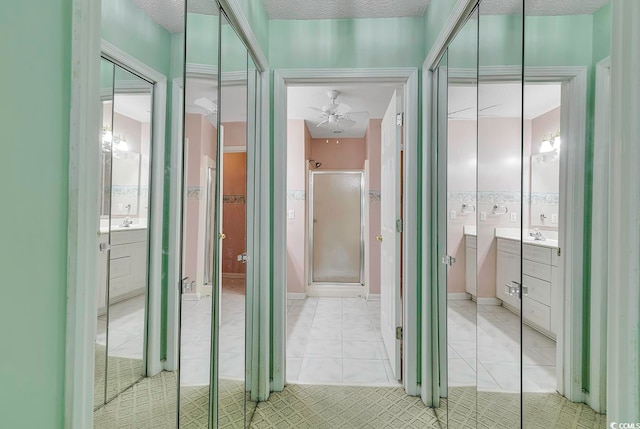 corridor with light tile patterned flooring, sink, and a textured ceiling