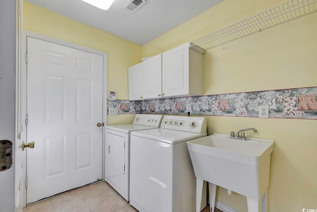 laundry area with cabinets, sink, independent washer and dryer, a textured ceiling, and light tile patterned floors