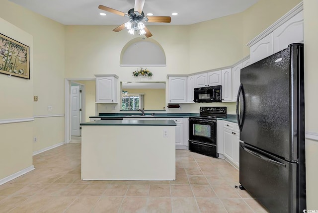 kitchen featuring a high ceiling, light tile patterned floors, white cabinetry, and black appliances