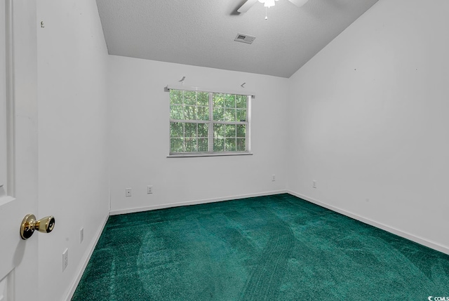 spare room with a textured ceiling, dark carpet, and lofted ceiling