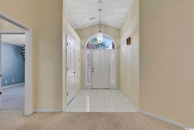 carpeted foyer with a textured ceiling, an inviting chandelier, and vaulted ceiling