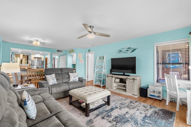 living room with light hardwood / wood-style flooring and ceiling fan