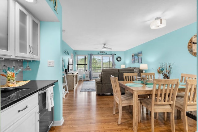 dining space featuring ceiling fan, beverage cooler, and light hardwood / wood-style flooring