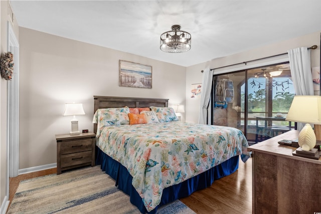 bedroom featuring access to outside, light hardwood / wood-style floors, and an inviting chandelier