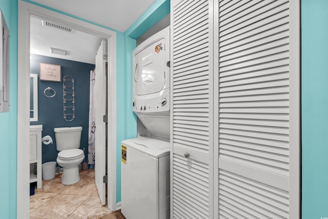 laundry room with stacked washer / drying machine and light tile patterned flooring