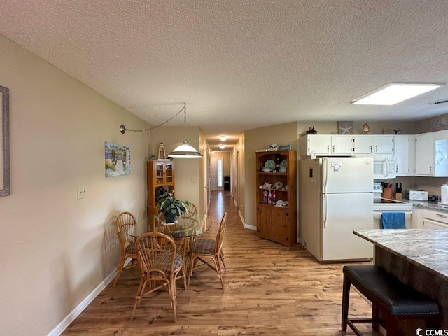 dining space featuring a skylight, light hardwood / wood-style flooring, and a textured ceiling