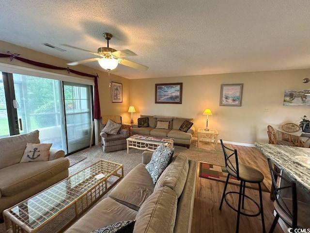 living room featuring wood-type flooring, a textured ceiling, and ceiling fan