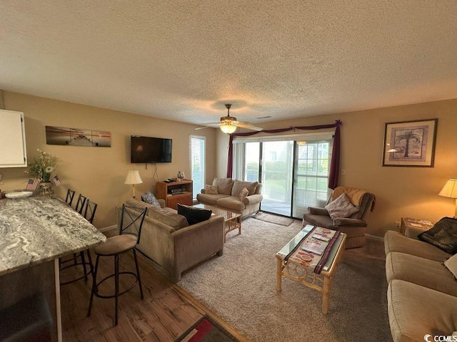 living room with hardwood / wood-style floors, a textured ceiling, and ceiling fan