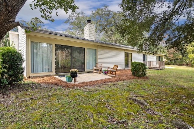 back of property with a lawn, a patio, and a wooden deck