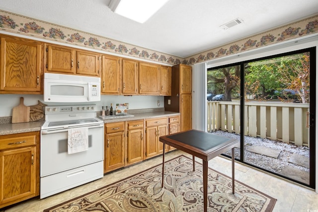 kitchen with a textured ceiling, light tile patterned floors, and white appliances