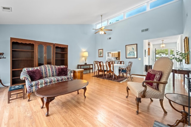 living room with ceiling fan, high vaulted ceiling, and light hardwood / wood-style floors