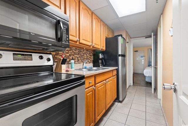 kitchen with sink, a drop ceiling, stainless steel appliances, decorative backsplash, and light tile patterned floors