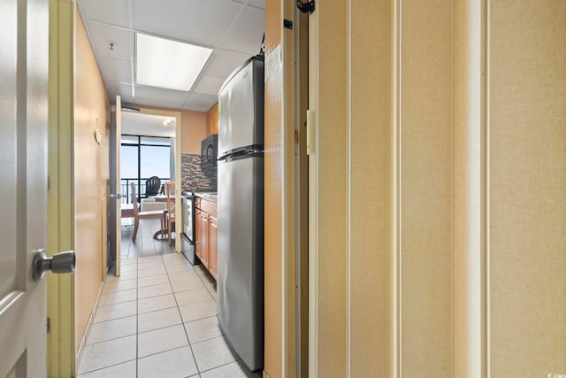 corridor with a drop ceiling and light tile patterned floors