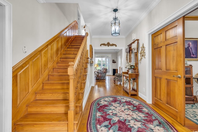 entrance foyer with hardwood / wood-style floors, crown molding, and an inviting chandelier