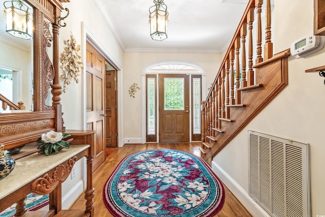 foyer entrance featuring a healthy amount of sunlight, crown molding, and light hardwood / wood-style floors