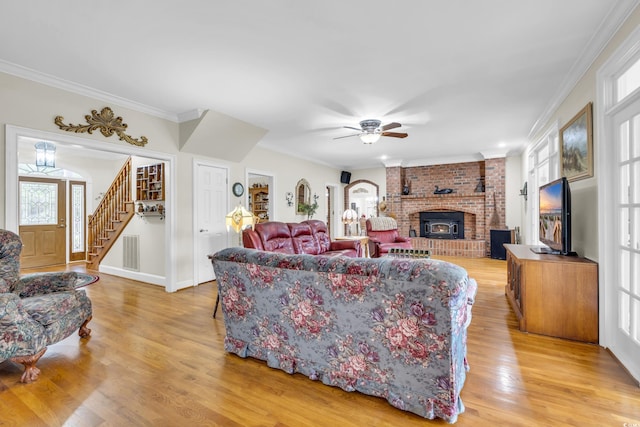 living room with a brick fireplace, ceiling fan, light hardwood / wood-style flooring, and ornamental molding