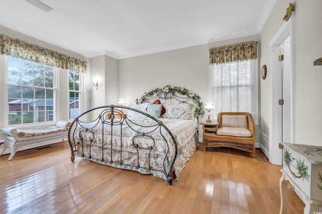 bedroom featuring multiple windows, wood-type flooring, and ornamental molding