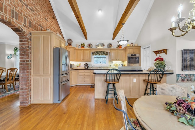 kitchen with hanging light fixtures, light brown cabinetry, a breakfast bar area, brick wall, and stainless steel appliances