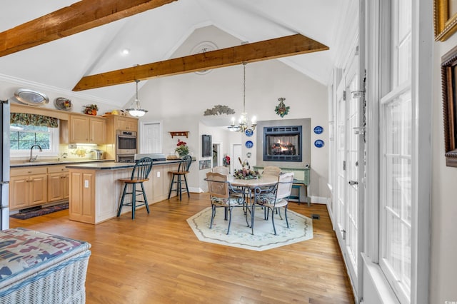 dining room featuring high vaulted ceiling, an inviting chandelier, sink, light wood-type flooring, and beam ceiling