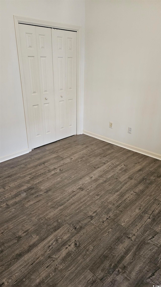 unfurnished bedroom featuring a closet and dark wood-type flooring