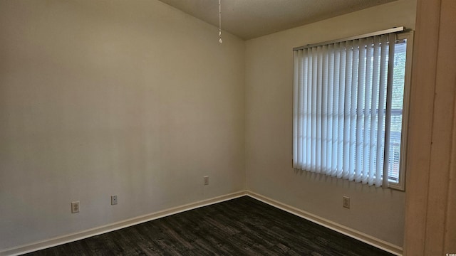 spare room with dark hardwood / wood-style flooring and a healthy amount of sunlight