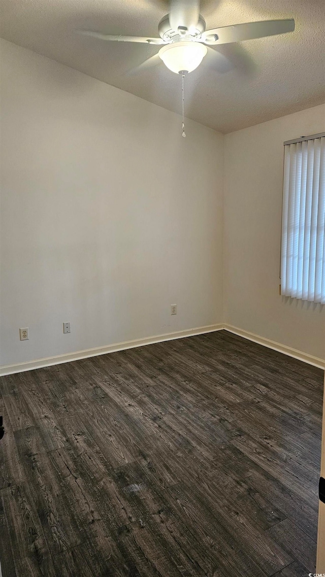 empty room with ceiling fan, dark wood-type flooring, and a textured ceiling