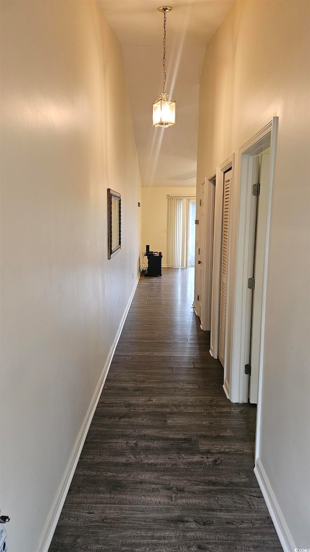 hall featuring dark hardwood / wood-style flooring, high vaulted ceiling, and an inviting chandelier