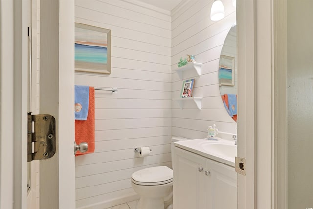 bathroom featuring wood walls, tile patterned flooring, vanity, and toilet