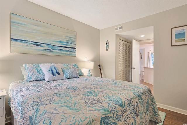 bedroom with hardwood / wood-style flooring, a textured ceiling, and a closet