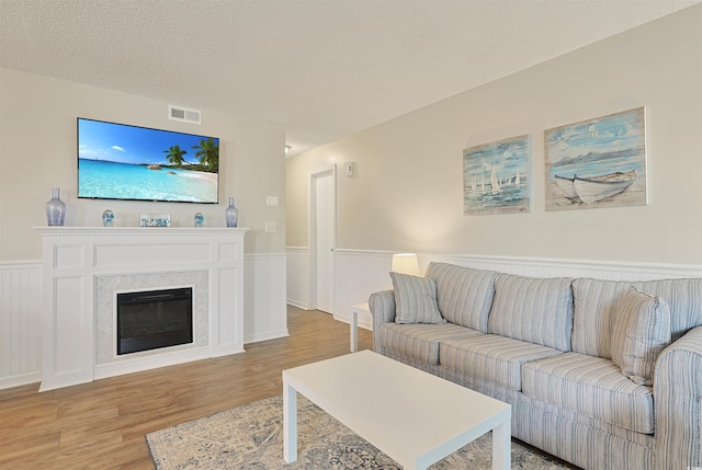 living room with a textured ceiling and light hardwood / wood-style flooring