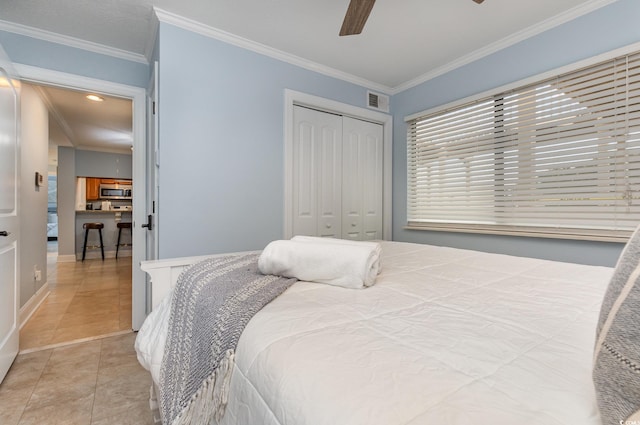 tiled bedroom with a closet, ornamental molding, and ceiling fan