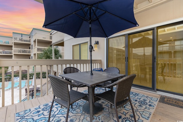 deck at dusk featuring a community pool