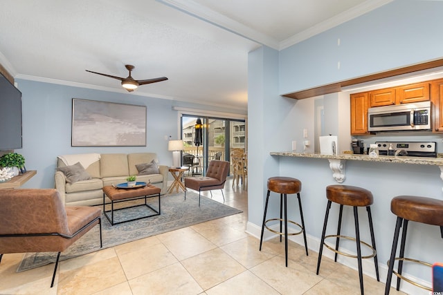 interior space featuring light stone countertops, ceiling fan, crown molding, a breakfast bar area, and appliances with stainless steel finishes