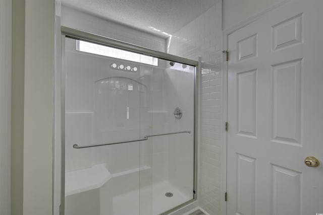 bathroom with a textured ceiling and walk in shower