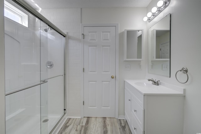 bathroom featuring a shower with door, vanity, a textured ceiling, and hardwood / wood-style flooring