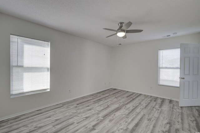 unfurnished room with a textured ceiling, light hardwood / wood-style flooring, a wealth of natural light, and ceiling fan