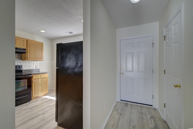 kitchen featuring black appliances, light hardwood / wood-style flooring, a textured ceiling, range hood, and tasteful backsplash