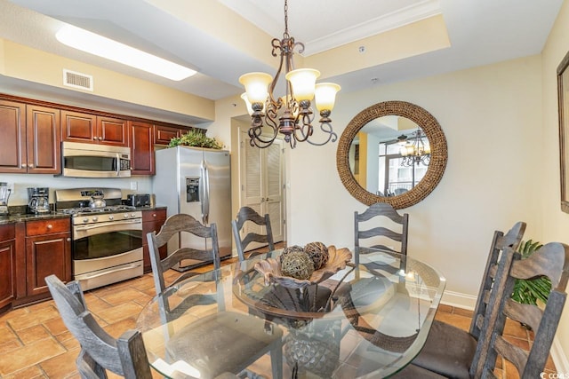 kitchen with a tray ceiling, pendant lighting, stainless steel appliances, and an inviting chandelier