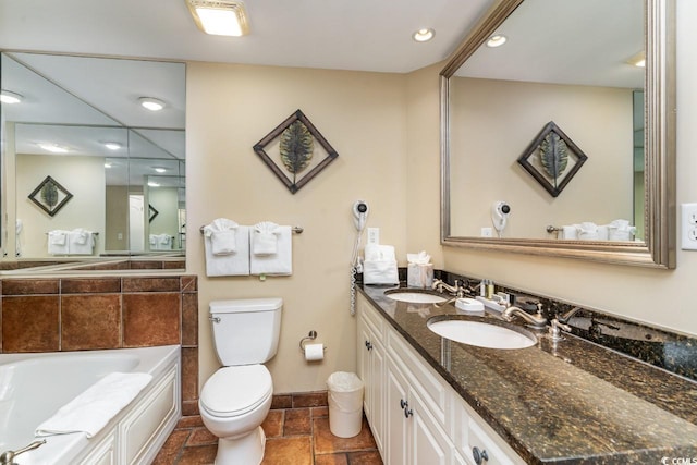 bathroom featuring vanity, tiled bath, and toilet