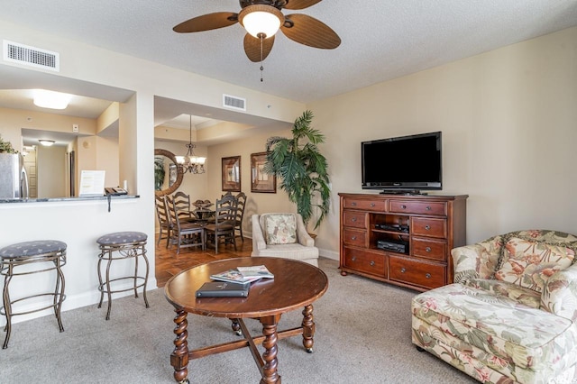 living room featuring light carpet, ceiling fan with notable chandelier, and a textured ceiling