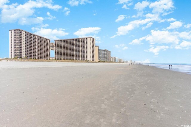 view of building exterior featuring a water view and a beach view