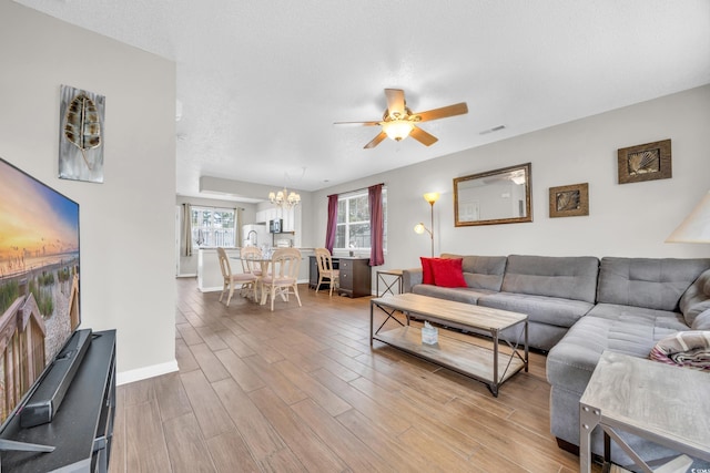 living room featuring a textured ceiling, hardwood / wood-style floors, and ceiling fan with notable chandelier