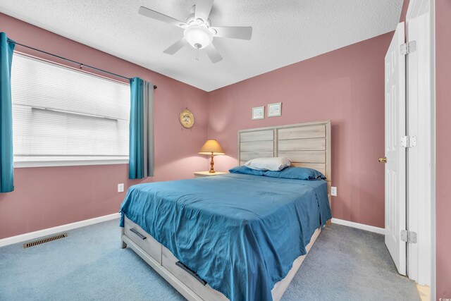 carpeted bedroom featuring ceiling fan and a textured ceiling