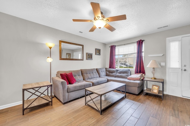 living room featuring ceiling fan, a textured ceiling, and light hardwood / wood-style flooring