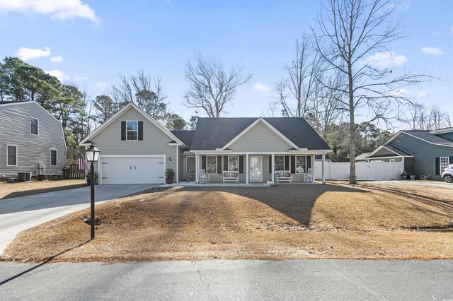 view of front of property with a garage, covered porch, a front yard, and central AC