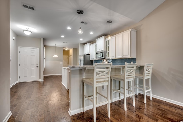 kitchen featuring dark hardwood / wood-style flooring, white cabinetry, kitchen peninsula, and appliances with stainless steel finishes