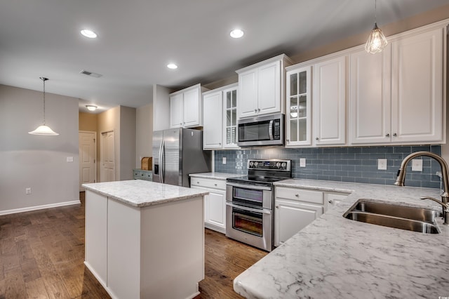 kitchen featuring a center island, dark wood-type flooring, sink, appliances with stainless steel finishes, and white cabinetry